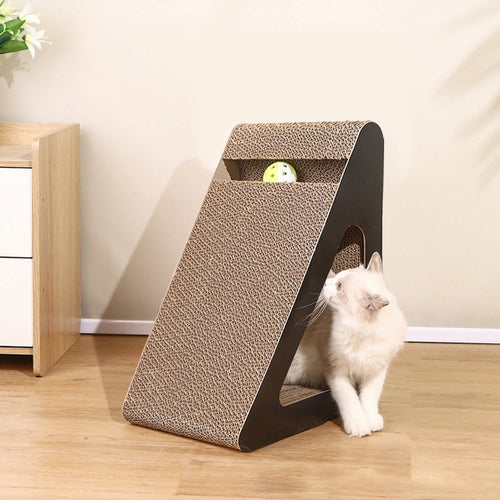 Triangle cat scratcher, cardboard with black frame, ball toy in top slot; fluffy cream cat sniffing beside it indoors